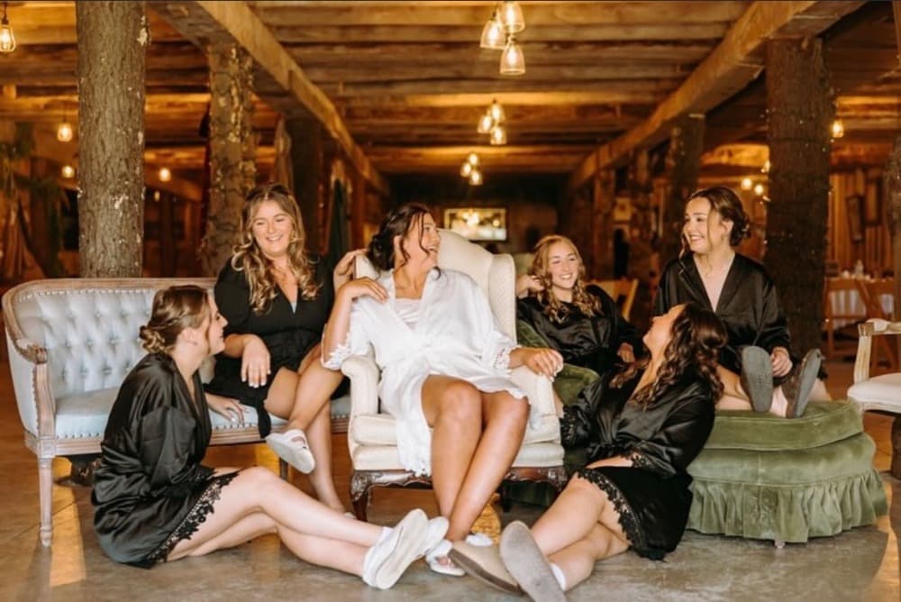 The bride and her bridesmaids laughing together while getting ready.